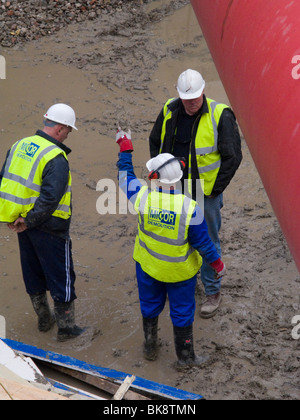 Les travailleurs de la construction avec des casques et des gilets haute visibilité parler à un édifice majeur / site de construction à Londres. Banque D'Images