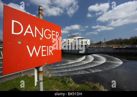 Danger weir signe en face de lagan valley Island et du centre des congrès avec weir sur la rivière Lagan lisburn city centre Banque D'Images