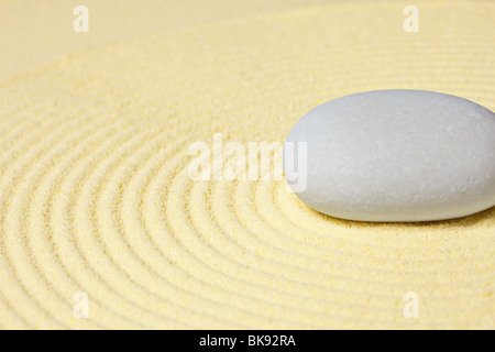 La pierre ronde couchée sur le sable jaune avec un modèle circulaire Banque D'Images