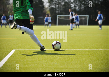 Un gardien efface un champ de football anglais lors d'un match de soccer/football amateur que le soleil bat vers le bas. Banque D'Images