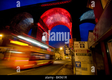 Une vitesse de bus sous un ancien viaduc de chemin de arch est éclairée la nuit par le chemin de fer confiance historique et Network Rail. Banque D'Images