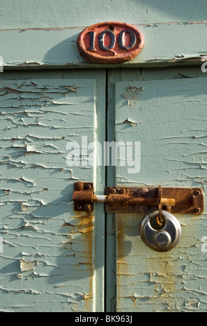 Une cabane de plage, numéro 100, sur Hove Esplanade, avec ses vis rouillées et cadenas. Banque D'Images