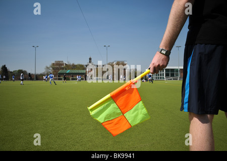 Un gros plan d'un juge de ligne's midrift lors d'un match de soccer ou de football amateur à Londres. La carte montre également un drapeau jaune et orange. Banque D'Images