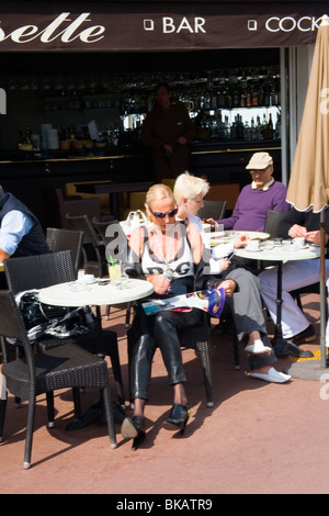 Cannes La Croisette , mature , dame d'âge moyen à presse citron boissons bar café vêtus de pantalons de cuir et chemisier D&G Banque D'Images