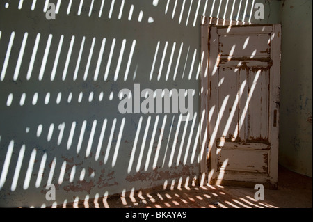 La lumière pénètre à travers le vieux plancher casting shadows sur les murs, Buchhalter Maison à Kolmanskop près de Lüderitz, Namibie Banque D'Images