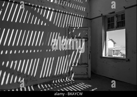 La lumière pénètre à travers le vieux plancher casting shadows sur les murs, Buchhalter Maison à Kolmanskop près de Lüderitz, Namibie Banque D'Images