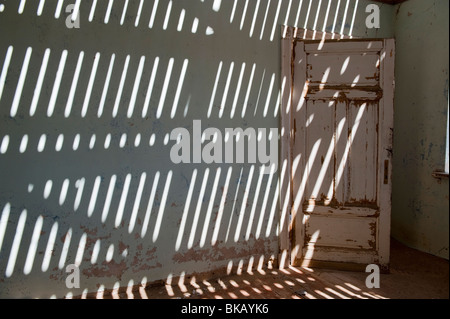 La lumière pénètre à travers le vieux plancher casting shadows sur les murs, Buchhalter Maison à Kolmanskop près de Lüderitz, Namibie Banque D'Images