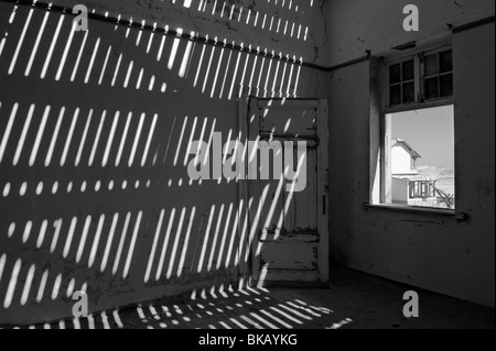 La lumière pénètre à travers le vieux plancher casting shadows sur les murs, Buchhalter Maison à Kolmanskop près de Lüderitz, Namibie Banque D'Images