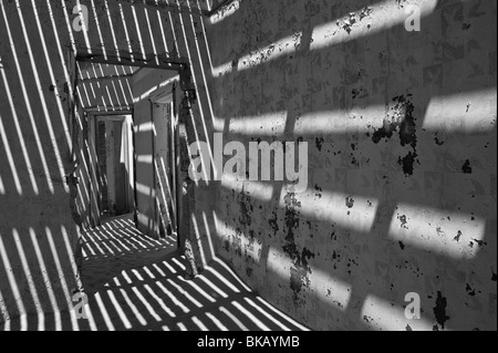 La lumière pénètre à travers le vieux plancher casting shadows sur les murs, les ingénieurs maison à Kolmanskop près de Lüderitz, Namibie Banque D'Images