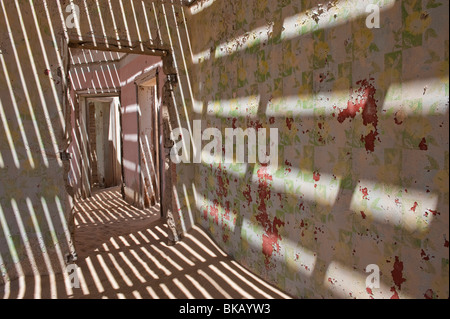 La lumière pénètre à travers le vieux plancher casting shadows sur les murs, les ingénieurs maison à Kolmanskop près de Lüderitz, Namibie Banque D'Images