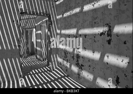 La lumière pénètre à travers le vieux plancher casting shadows sur les murs, les ingénieurs maison à Kolmanskop près de Lüderitz, Namibie Banque D'Images