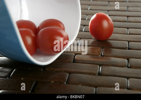 Groupe des tomates cerise tombant de plus tablacloth bol bleu brun Banque D'Images