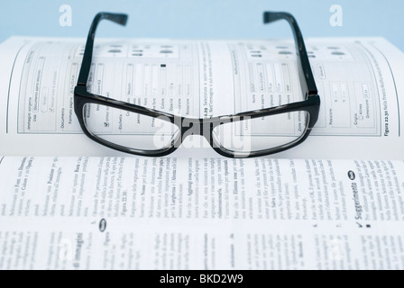 Couché sur un lunettes livre manuel Banque D'Images