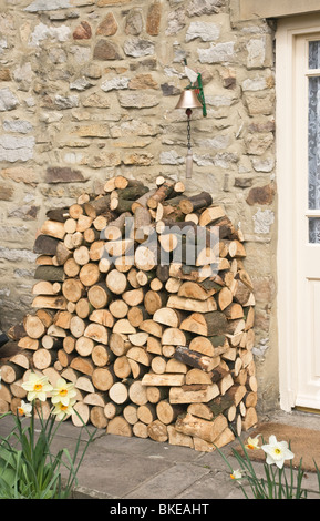 Bois de chauffage empilé en dehors d'une porte du chalet dans le Yorkshire Dales. Banque D'Images