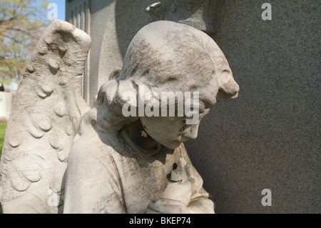 Statue d'un ange genuflecting dans une position servile, partie d'un cimetière. Banque D'Images