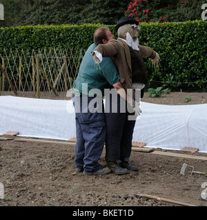 Déménagement jardinier un épouvantail devant le binage et la plantation des légumes à Heligan Gardens Cornwall dans l'Ouest Pays Angleterre UK Banque D'Images