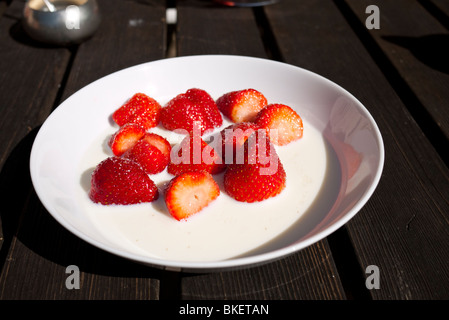 Plaque avec des fraises fraîches avec de la crème sur la table. Banque D'Images