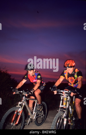 Man and Woman riding bikes au coucher du soleil. Banque D'Images