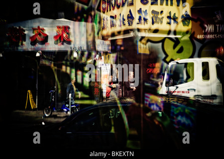 Reflet dans une vitrine de magasin chinois signes sur la 40e Avenue, Flushing, New York USA Banque D'Images