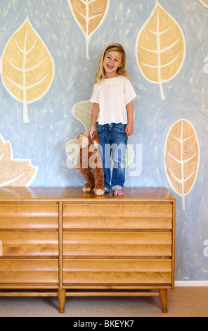 Jeune fille debout sur une commode Banque D'Images