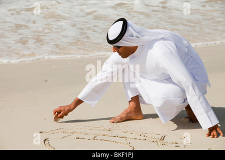Un homme portant un costume traditionnel arabe sur une plage à Dubaï Banque D'Images