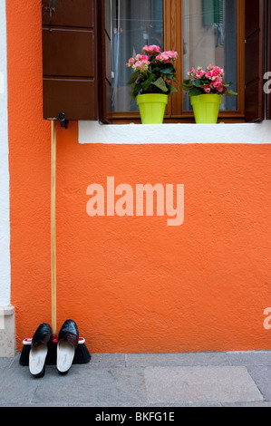 Détail de chaussures reposant sur un balai à l'extérieur chambre orange colorée à Burano près de Venise Italie Banque D'Images