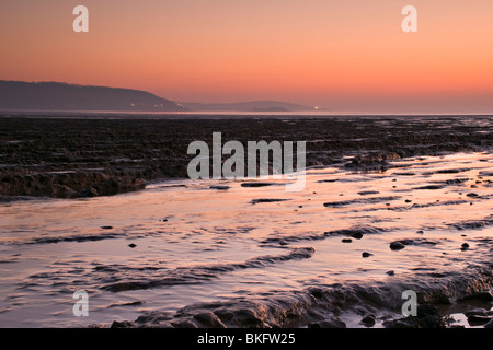 Coucher de soleil sur les vasières à Sandpoint, près de Weston Super Mare, en Angleterre avec les lumières au Weston tout juste visible dans la distance Banque D'Images