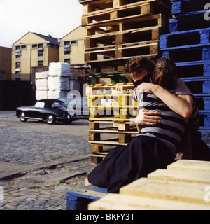 Jeune couple hugging in parking de caisses vides et une fantaisie voiture suranné, à l'arrière-plan Banque D'Images