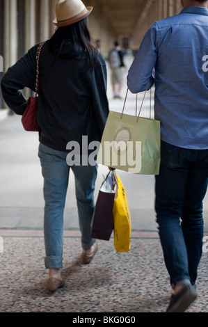 Couple marchant avec des sacs de shopping de vacances, des jardins du 'jardin du Palais Royale' à Paris, France, adolescents urbains à la mode, femme portant des sacs de shopping dans la rue principale Banque D'Images