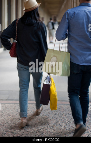 Couple marchant avec des sacs de shopping de vacances, des jardins du 'jardin du Palais Royale' à Paris, France, des adolescents urbains à la mode Banque D'Images