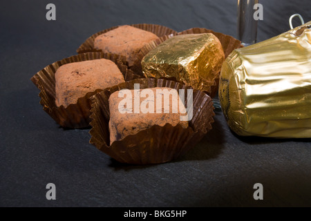 Le commerce équitable de luxe Champagne truffes au chocolat, saupoudrées de poudre de cacao sur arrière-plan foncé de l'ardoise. Banque D'Images