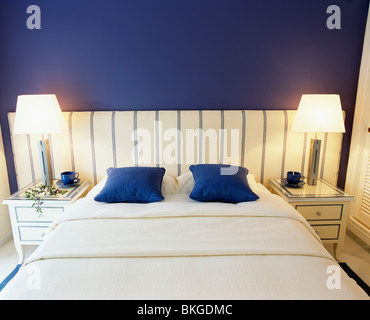 Des lampes sur les tables de chevet de chaque côté du lit avec coussins bleu et blanc en couverture de lit chambre bleu vif Banque D'Images