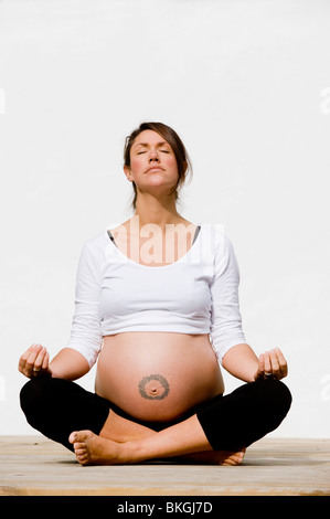 Une femme enceinte s'étire faisant yoga en douceur et la méditation en préparation de son bébé Banque D'Images