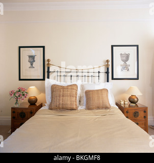 Photos sur mur au-dessus de bad en laiton avec coussins à motifs beige et beige double-couverture en appartement chambres avec des lampes allumées Banque D'Images