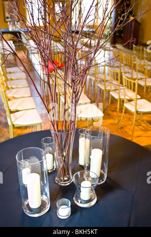 Un lieu de réception de mariage, avec des branches dans un vase et des bougies sur une table à l'avant-plan. Banque D'Images