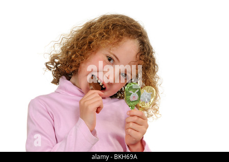 Fillette de six ans avec une dent avant de manger une barre de chocolat sur un bâton Banque D'Images