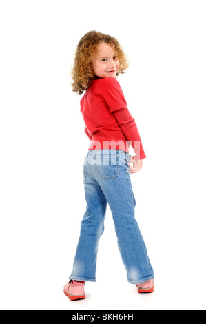 Fillette de six ans avec une dent de devant porter un jean bleu et une chemise rouge avec des sandales pose pour la caméra Banque D'Images