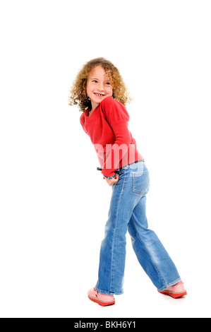 Six ans, fille, porter un jean bleu et une chemise rouge avec des sandales pose pour la caméra Banque D'Images