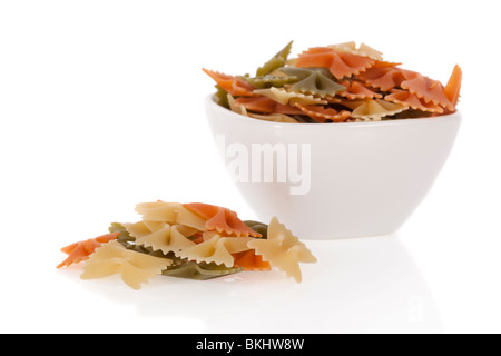 Pâtes farfalle tricolore dans un bol isolé sur fond blanc Banque D'Images