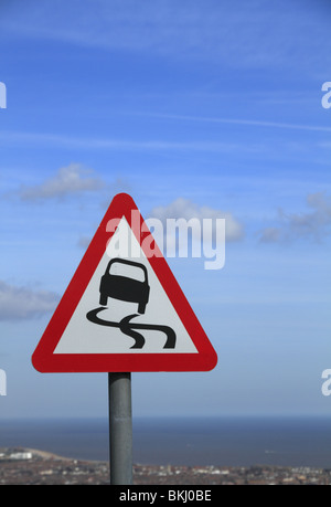 Un panneau routier avise les automobilistes de la surface glissante potentiellement près de Eastbourne, East Sussex Banque D'Images