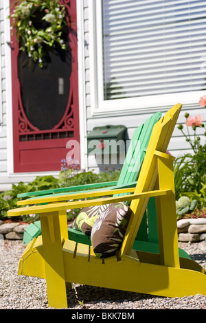 L'avant d'un chalet avec deux chaises Adirondack aux couleurs vives et d'une couleur tout aussi porte avant. Banque D'Images