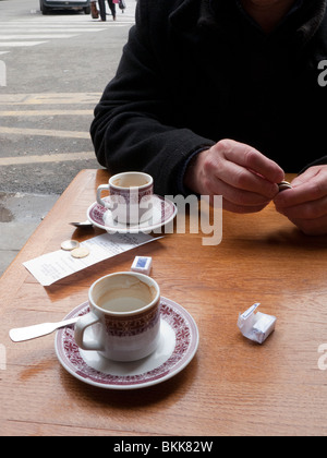 Homme mature assis devant un café à Paris Banque D'Images