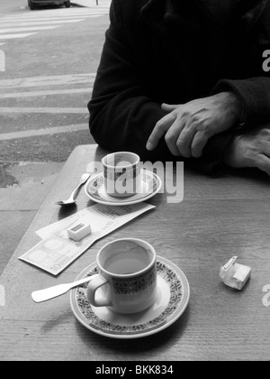 Homme mature assis devant un café à Paris Banque D'Images