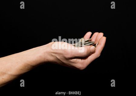 Homme de race blanche (42 ans) avec main tendue pleine d'argent sur un fond noir Banque D'Images