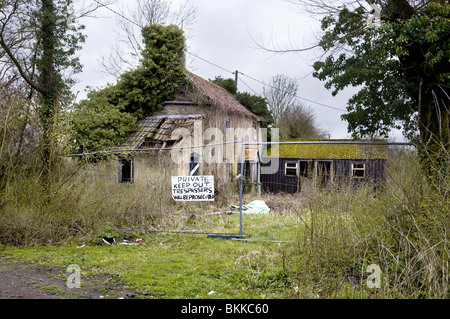 Maison abandonnée , abandonné derrière la haute clôture avec garder hors des signes. Banque D'Images