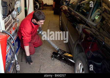 L'aide mécanicien cric de levage pour voiture dans un garage Banque D'Images