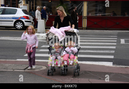 Mère portant deux fils dans une poussette ou buggy avec sa petite fille dans les rues Banque D'Images