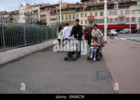 Mère et père exerçant son fils et sa fille à deux poussettes ou landaus dans les rues Banque D'Images