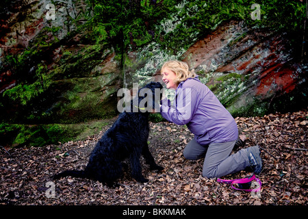 Joue avec sa femme Labradoodle chien tandis qu'en face de rochers sur un pays à pied Banque D'Images