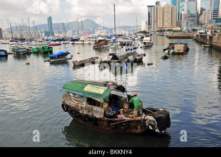 L'homme, vêtu d'un chapeau de paille, debout sur l'avant d'un sampan péniche, dans les eaux de la Causeway Bay, Hong Kong Hébergement typhon Banque D'Images